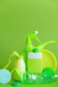 Assorted green cleaning supplies against vibrant green backdrop, promoting eco-friendly sanitation.