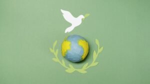 Conceptual image of a paper dove over Earth with olive branches, symbolizing peace.