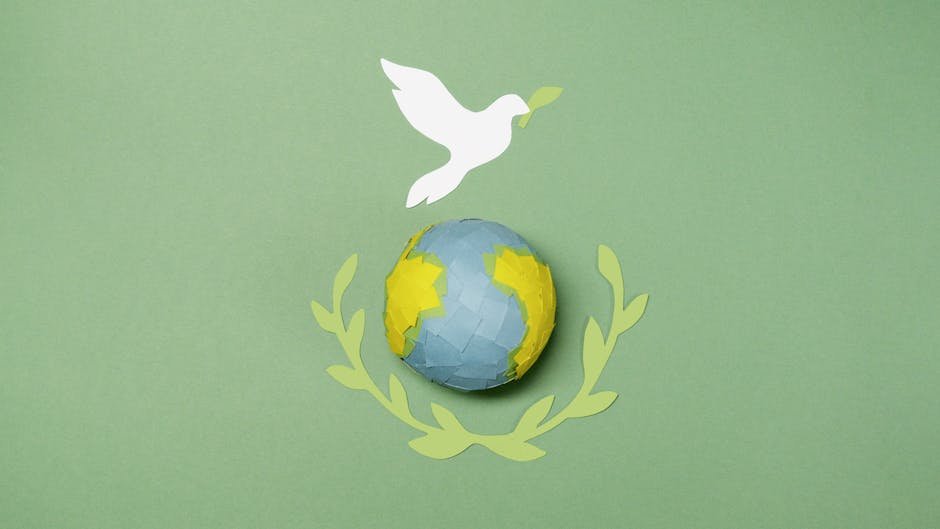 Conceptual image of a paper dove over Earth with olive branches, symbolizing peace.